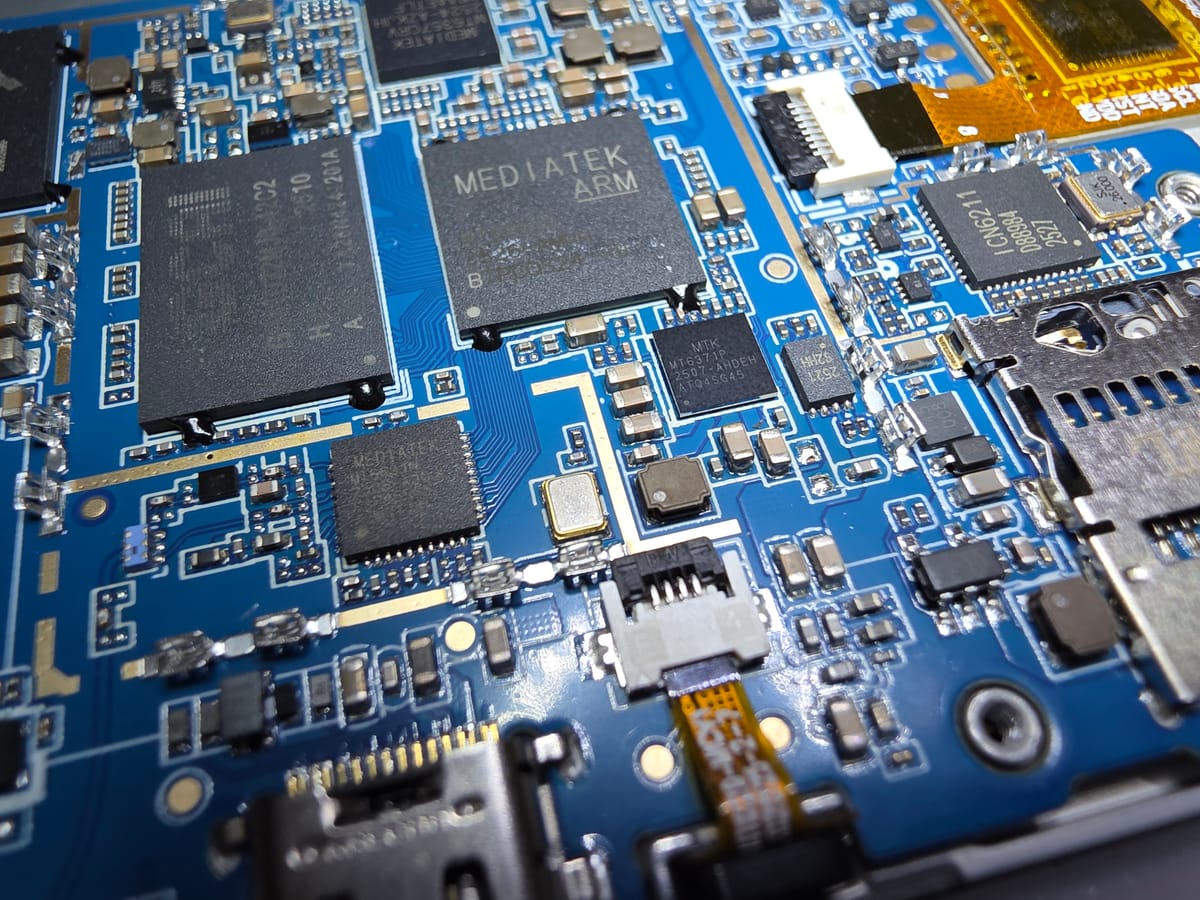 Close up of the guts of the tablet, a bunch of different ICs on a blue PCB. A Mediatek logo is visible on one of the biggest ICs but its part number is not readable from that angle.